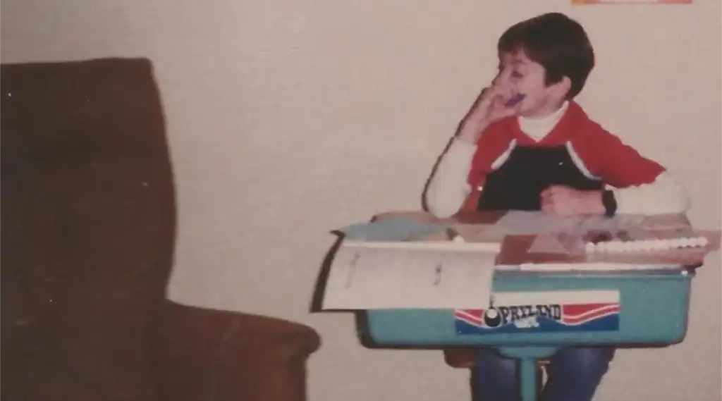 Young Sabrina Cleary sitting thoughtfully at a small school desk.